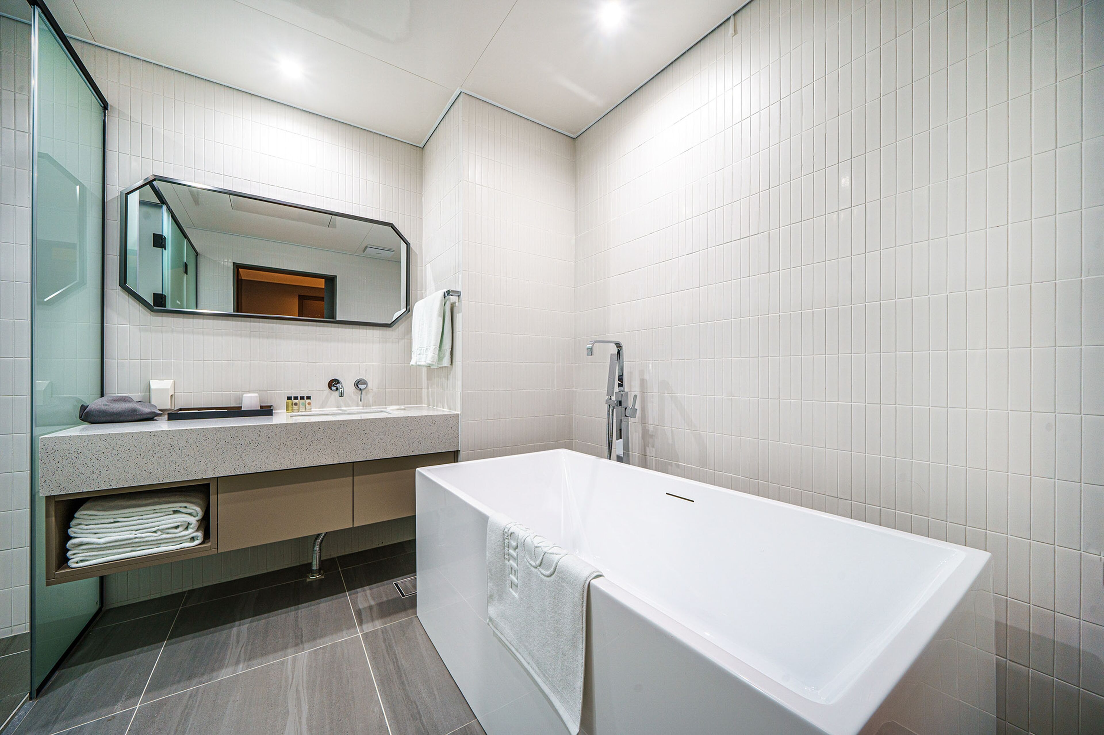 A modern bathroom with a freestanding bathtub, a large mirror, and a vanity with a countertop.