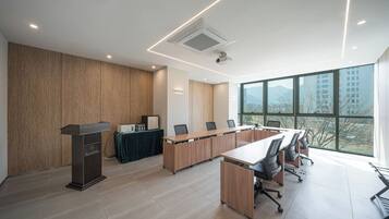 Una sala de conferencias moderna con una larga mesa, sillas, un atril y un amplio ventanal con vista a la ciudad.