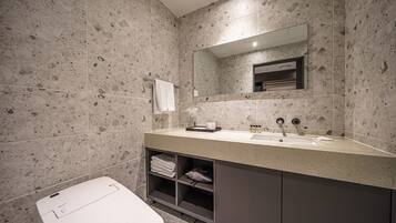 A modern bathroom with a large mirror, a sink, and a toilet.