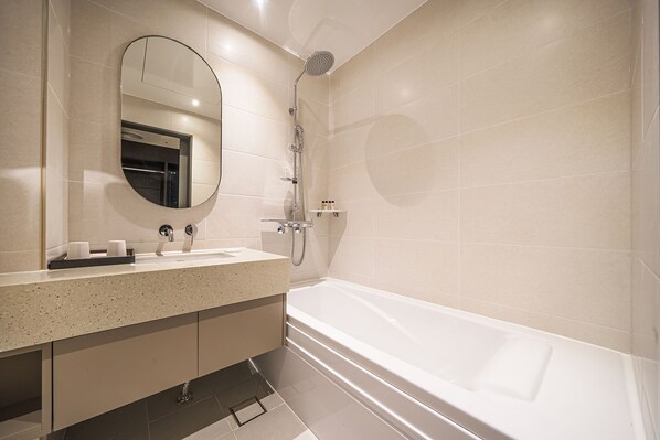 Un baño moderno con una bañera independiente, un espejo redondo y una encimera con artículos de aseo.
