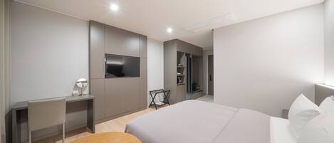 A modern hotel room with a large bed, a desk, a chair, and a TV.