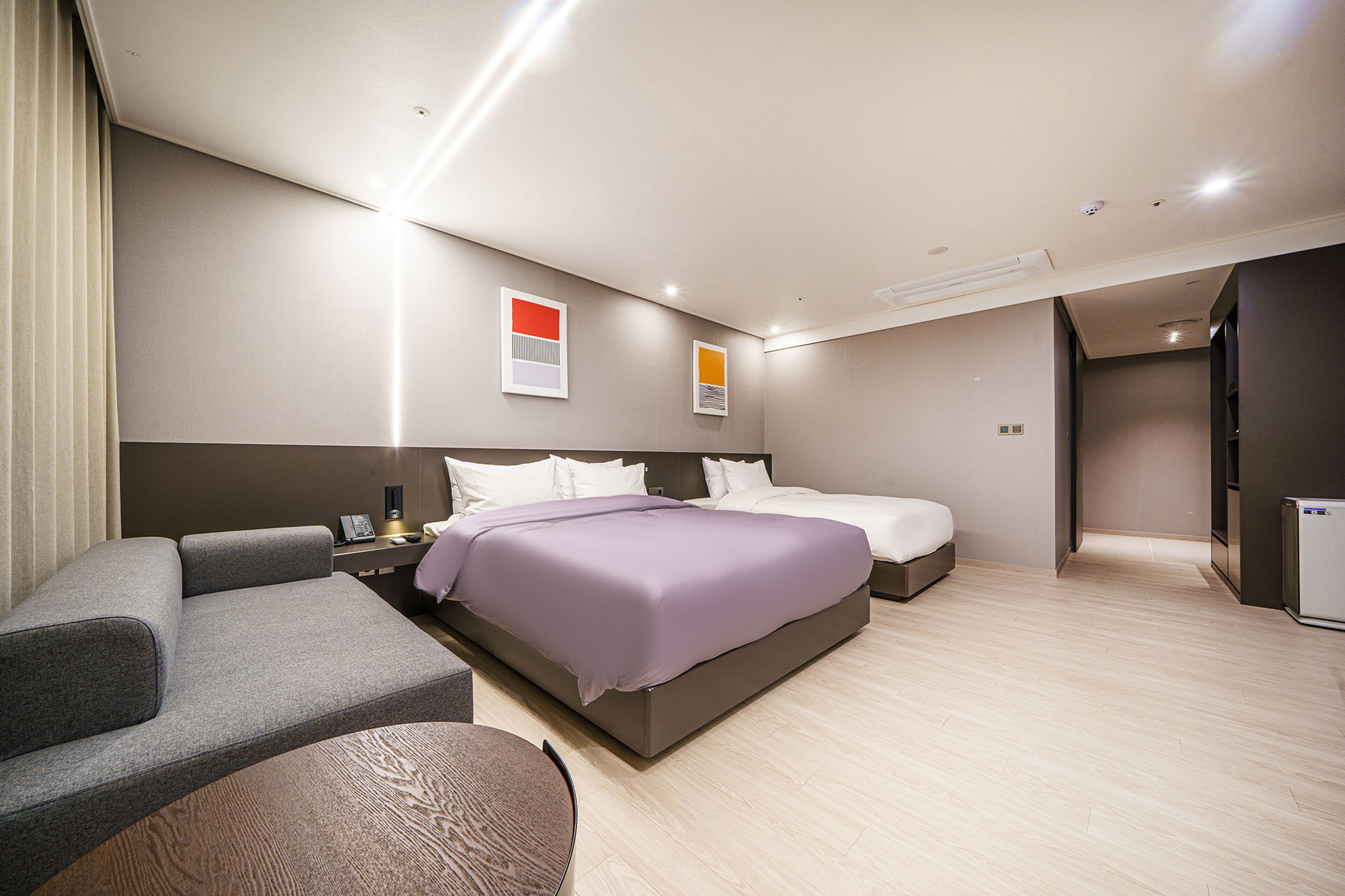 Una habitación de hotel moderna con una cama grande, un sofá y un escritorio con lámpara.