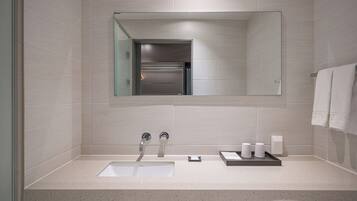 A modern bathroom with a large mirror, a sink, and a towel rack.