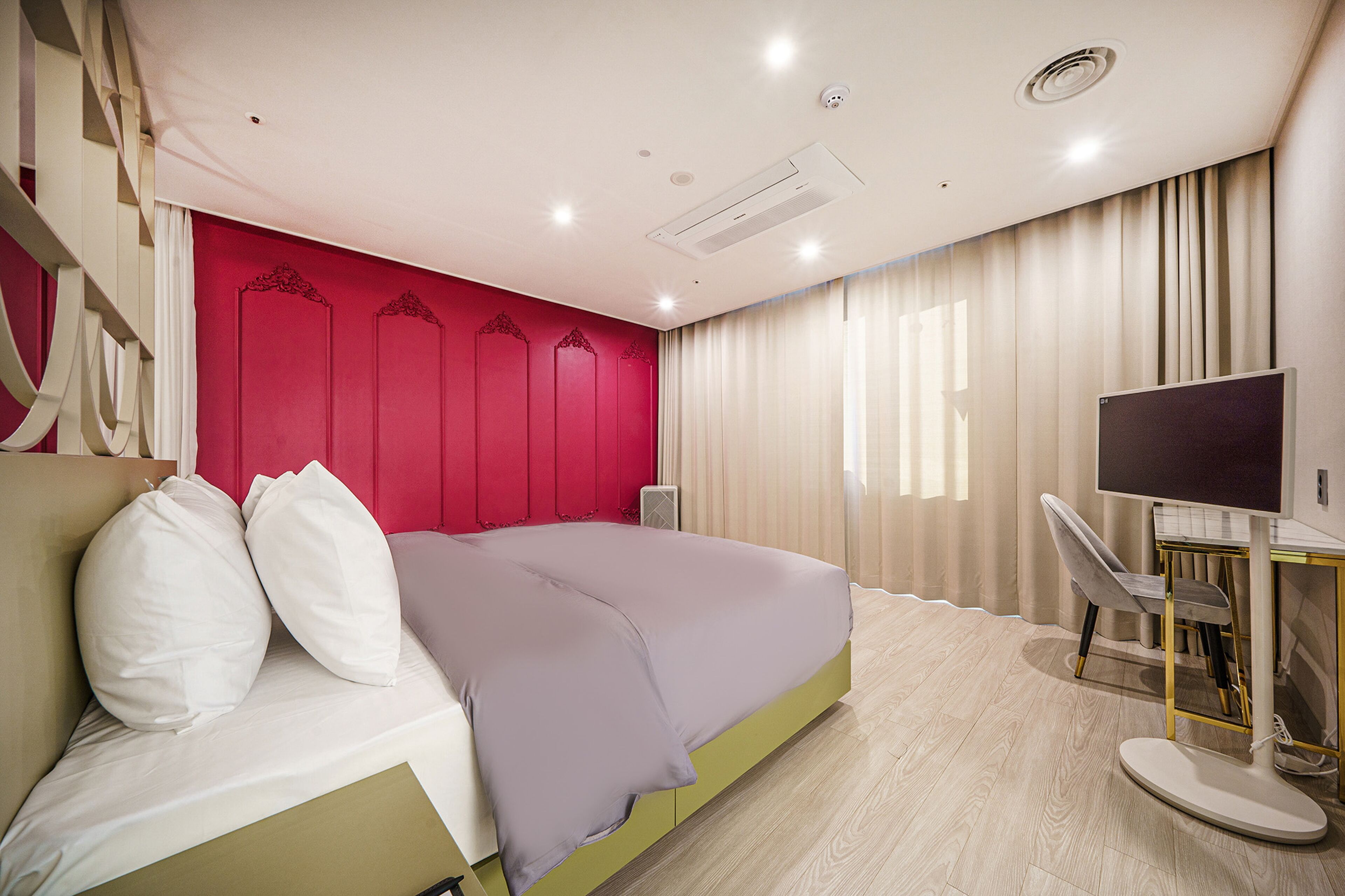 Ein modernes Schlafzimmer mit Bett, Schreibtisch und Fernseher.