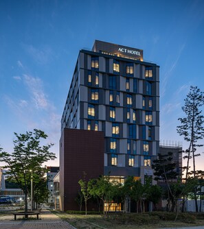 Un hôtel moderne, composé de plusieurs étages, avec une enseigne indiquant « ACT HOTEL ».