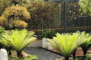 A garden with large green plants, a stone pathway, and a wooden fence. - Yuxi Jiada Hotel (Yuxi)