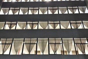 Fachada de edificio con varias ventanas, cada una con cortinas.