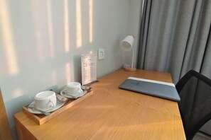 Ein Holztisch mit einem Laptop, einer Speisekarte und einer Ablage mit zwei Tassen und Untertassen.