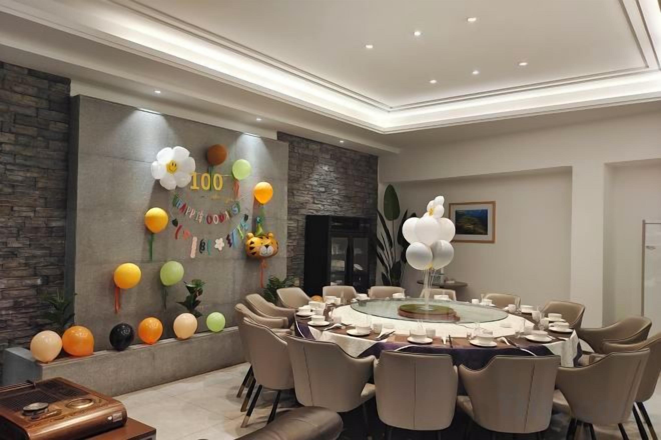 A conference room with a round table, chairs, and a decorative wall with balloons and a banner.