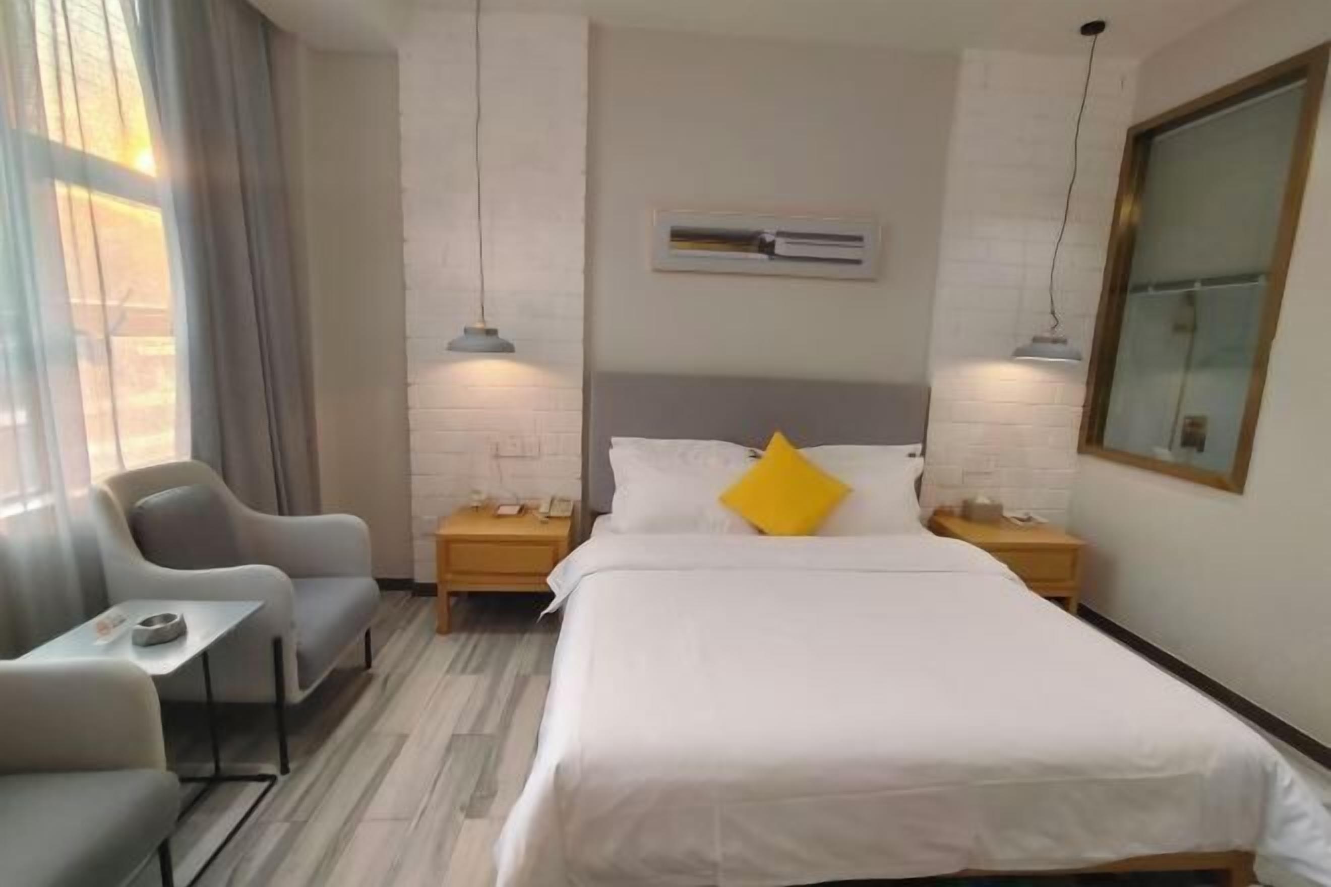 A hotel room with a bed, two bedside tables, a small table with a chair, and a couch.