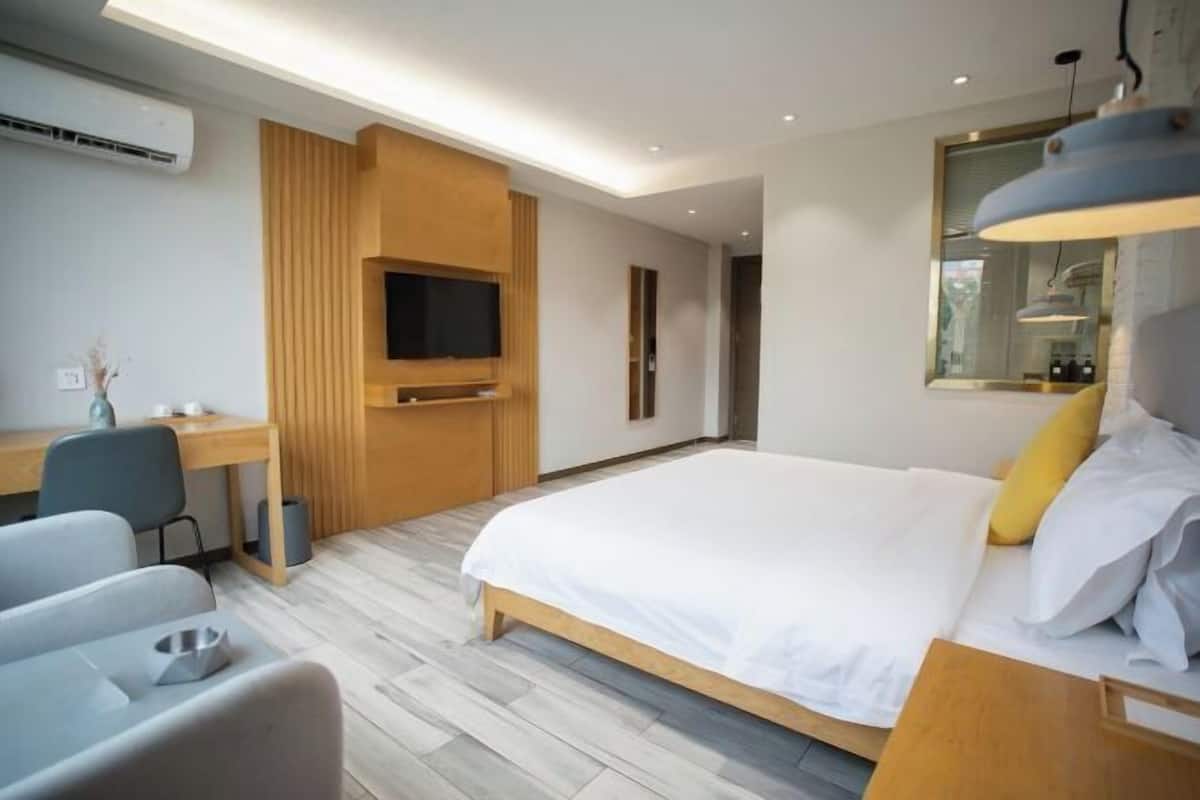 A modern hotel room with a large bed, a desk, a chair, and a television.