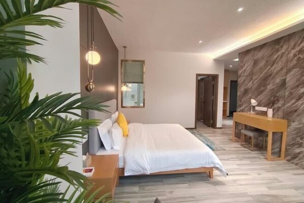 A modern bedroom with a bed, bedside table, and a desk with a chair.