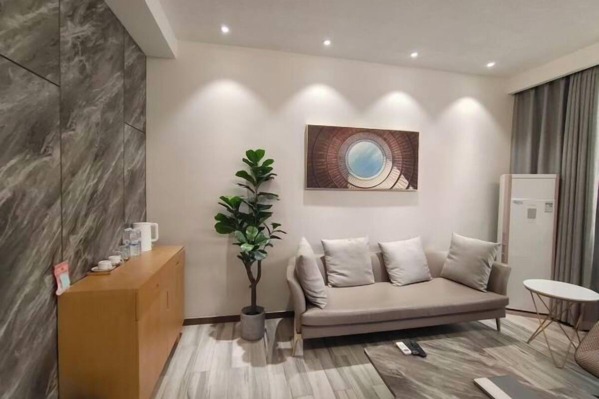A modern living room with a sofa, a coffee table, a plant, and a painting on the wall.