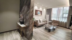 Una sala de estar moderna con sofá, sillones, una mesa de centro y un cuadro en la pared.