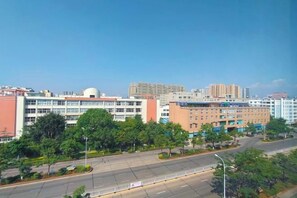 Un edificio de varios pisos con techo plano y una gran estructura en forma de cúpula, rodeado de árboles y cielo despejado.