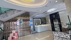 Eine Hotelhalle mit einer Rezeption, einem Kronleuchter und einer Treppe.