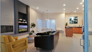 Una sala de estar moderna con chimenea, un sofá, un comedor y una cocina.