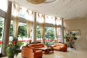 Un vestíbulo amplio con ventanas grandes, una zona de estar con sofás y un techo decorativo.