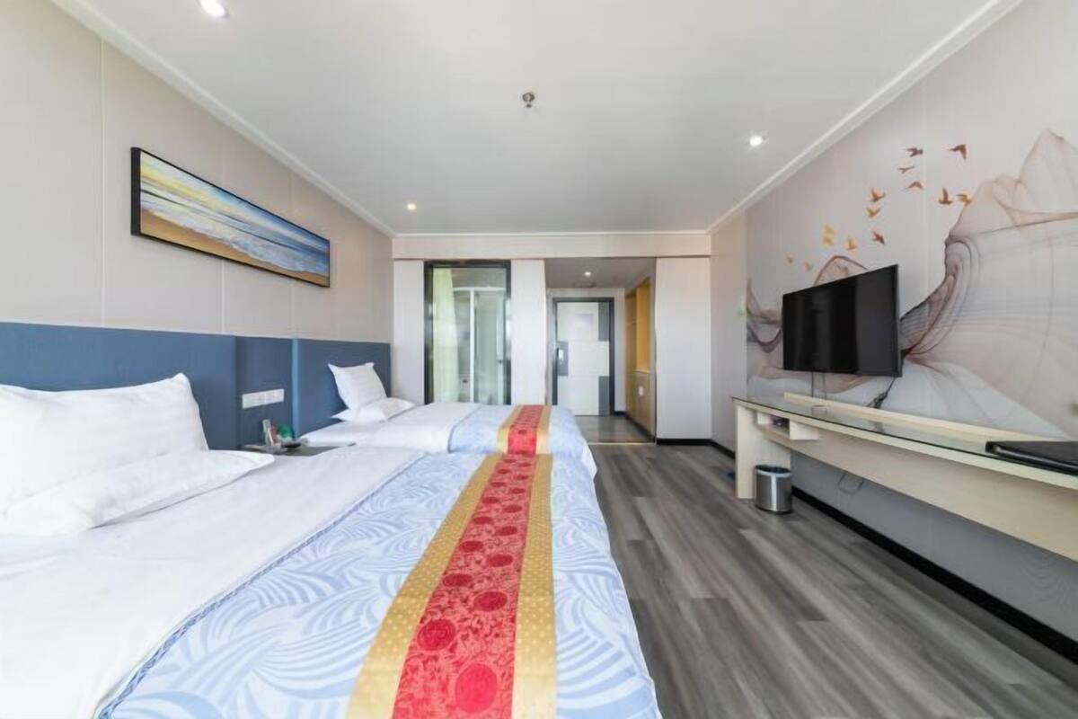 Una habitación de hotel con cama, televisión y una pared con un cuadro.