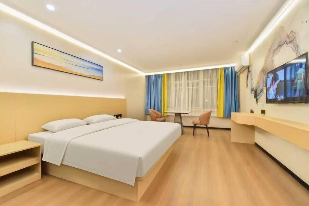 Habitación de hotel moderna con una cama grande, un escritorio, una silla y una televisión.