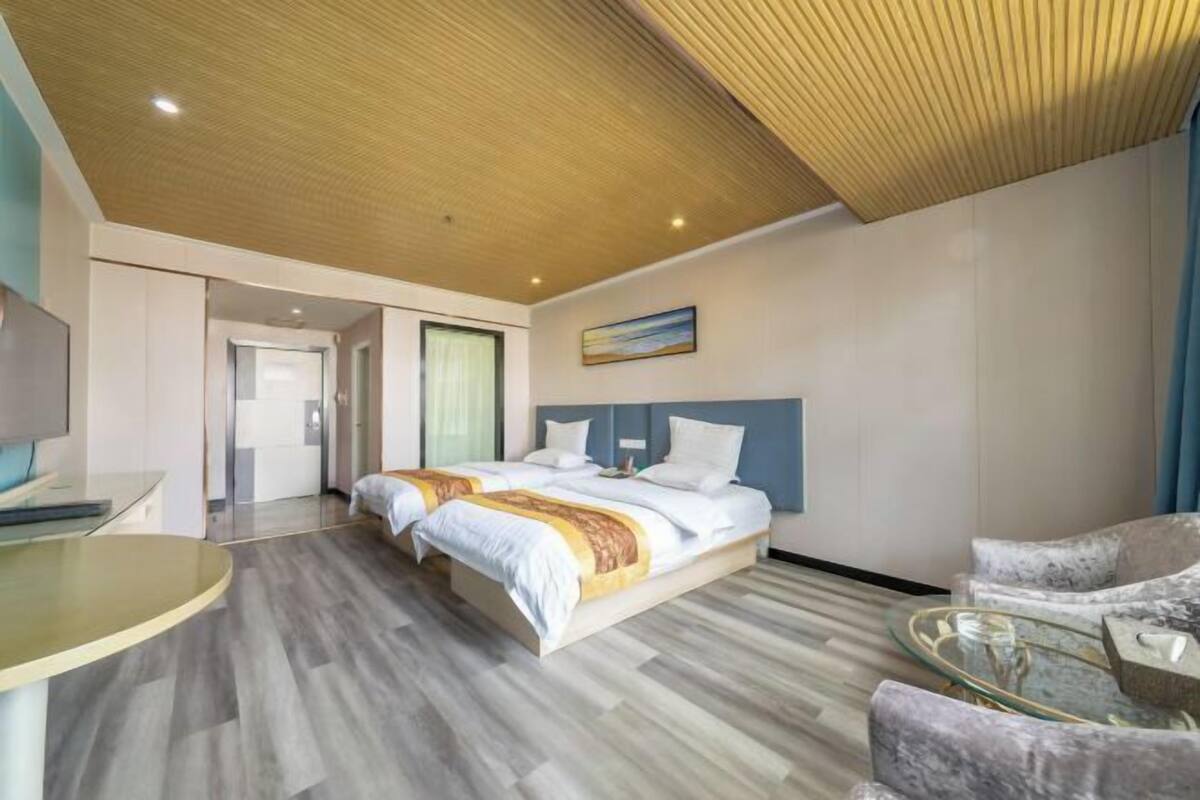 Una habitación de hotel moderna con una cama grande, un escritorio y una mesa de centro de vidrio.