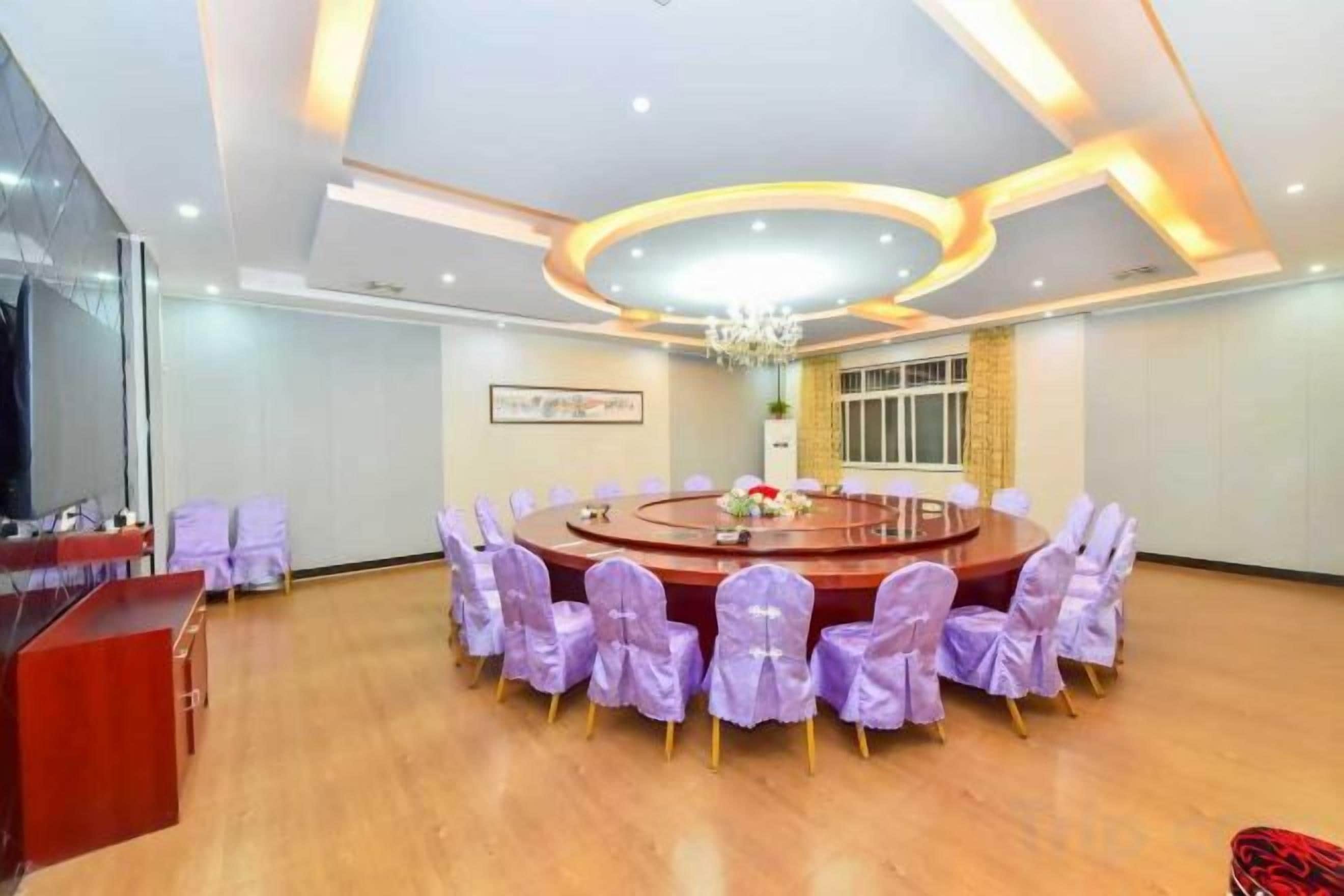 A conference room with a round table, chairs, and a television.