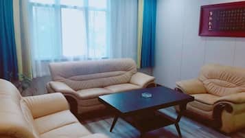 A living room with beige sofas, a black coffee table, and a large window with blue curtains.
