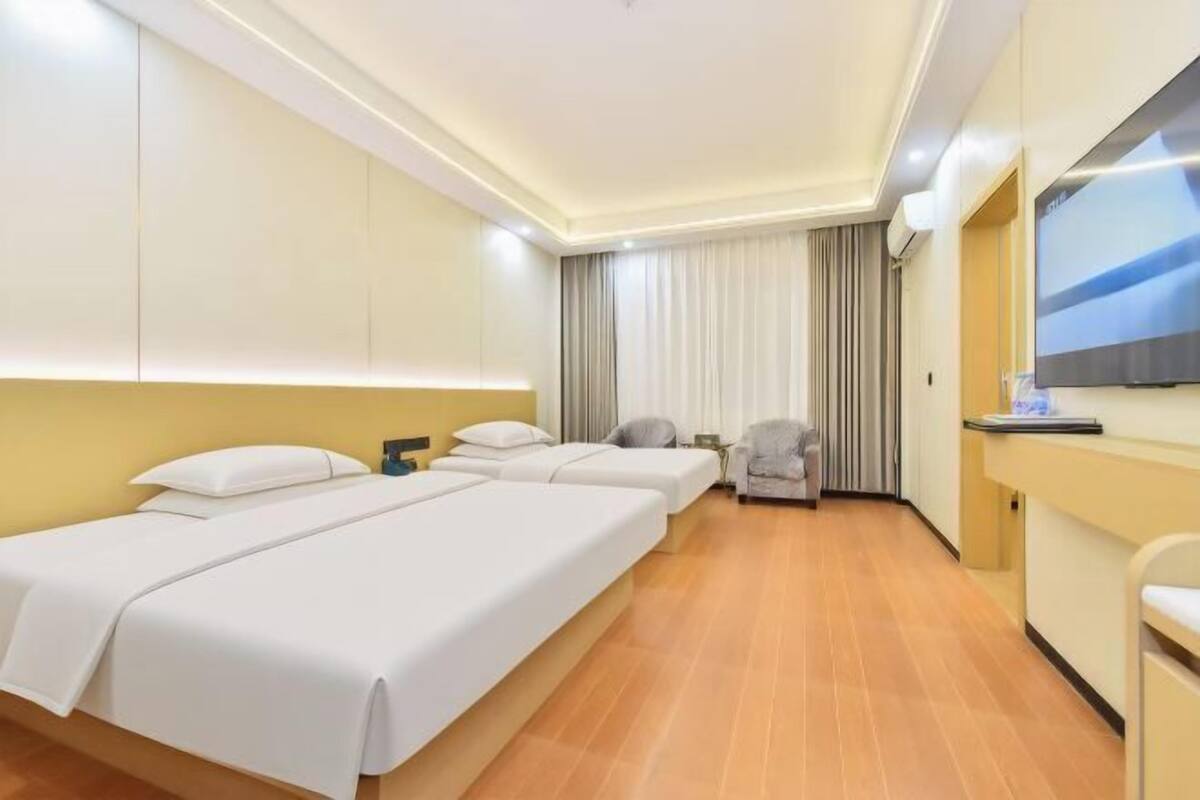 Una habitación de hotel con dos camas, televisión, escritorio y una silla.