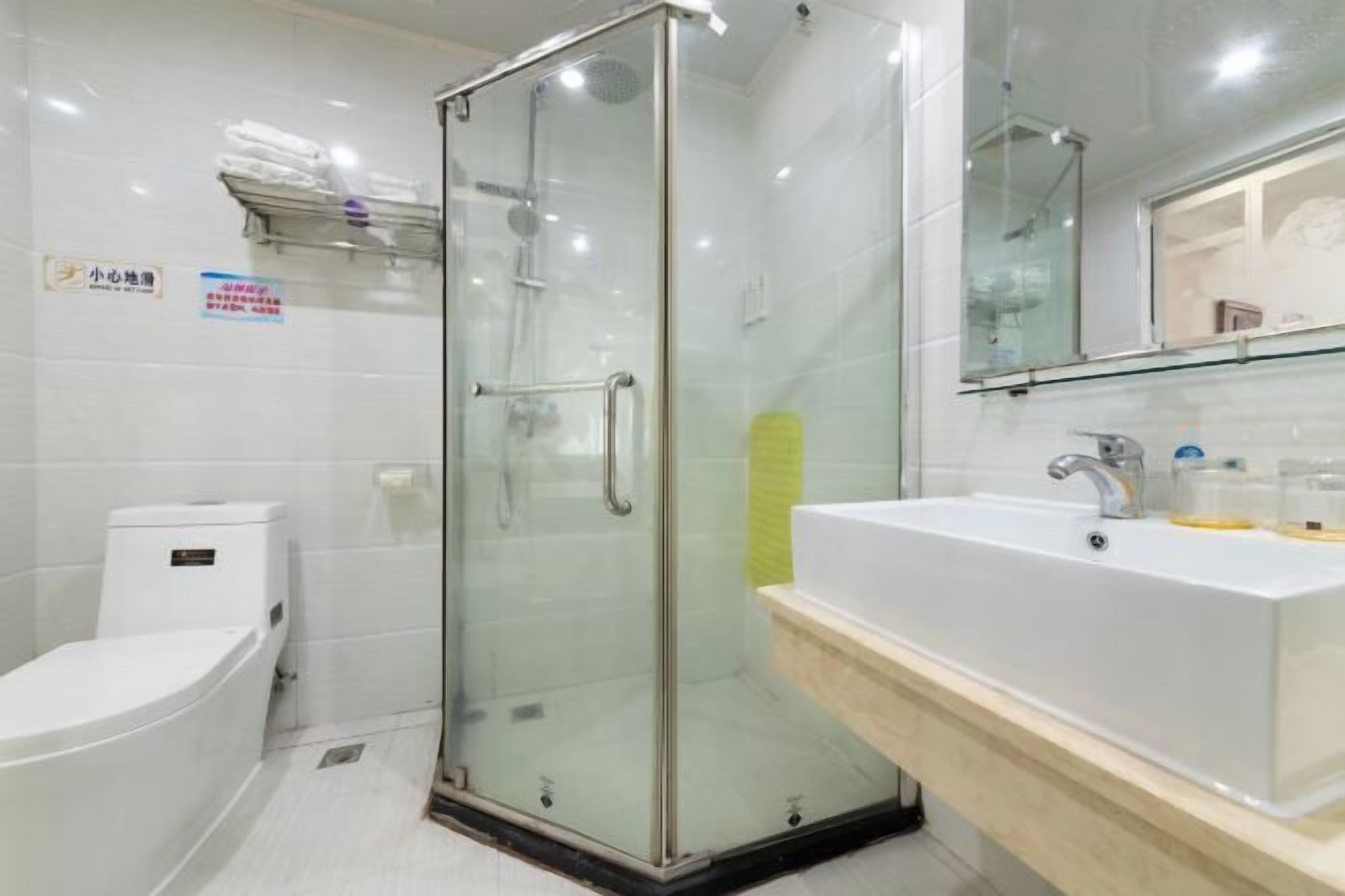 A modern bathroom with a glass shower enclosure, a white sink, and a toilet.