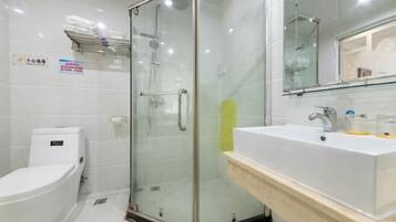 A modern bathroom with a glass shower enclosure, a white sink, and a toilet.