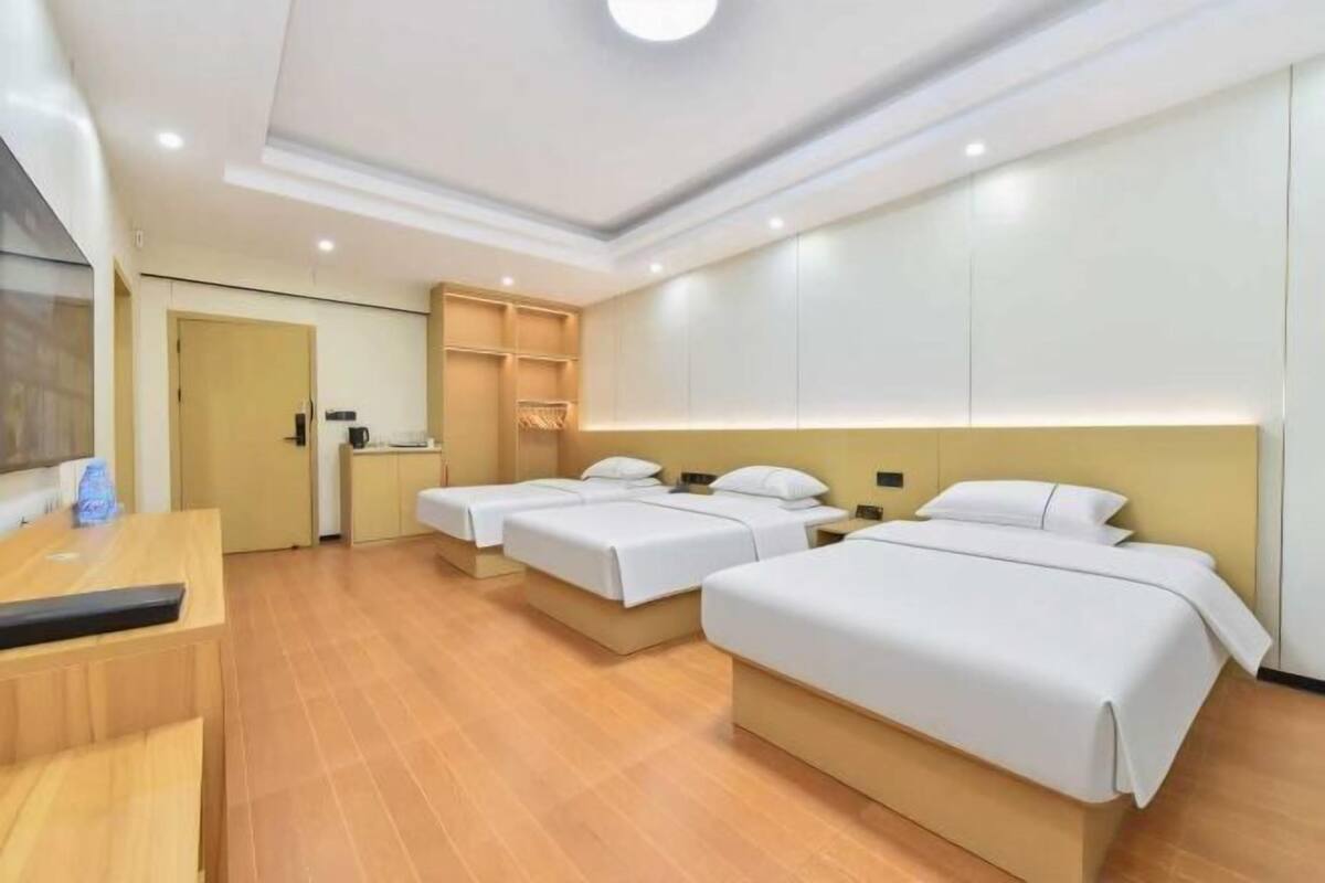 Una habitación de hotel con tres camas, un escritorio y un armario.