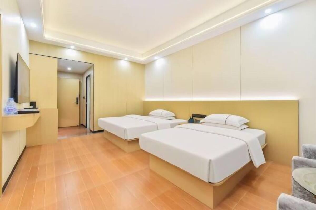 Habitación de hotel con dos camas, televisión, escritorio y una silla.