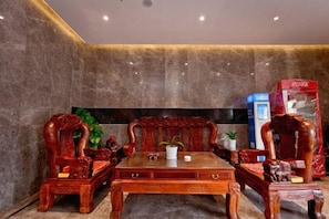 A room with a wooden table and chairs, a flat-screen TV, and a red box on the right. - Fujia Business Hotel (Fuyang)