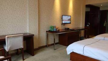 A hotel room with a bed, a desk, a chair, a television, and a minibar.