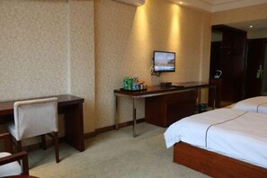 A hotel room with a bed, a desk, a chair, a television, and a minibar. - Fujia Business Hotel (Fuyang)