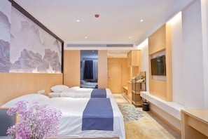 A hotel room with two beds, a desk, a TV, and a large artwork on the wall.