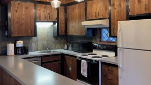 Une cuisine avec des meubles en bois, un îlot central et des luminaires suspendus.