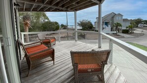 A covered porch with wicker furniture and a view of a residential area. - Private Murrells Inlet Waterfront 4 Bedroom 4 Bath Home on Marsh with Fire Pit (Murrells Inlet)