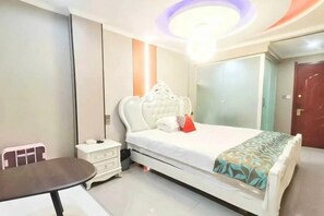 A bedroom with a bed, bedside table, and a small table with chairs. - Suzhou Jiale Hotel (Suzhou)