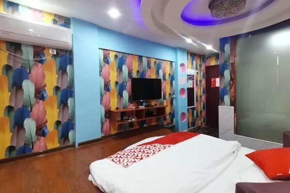 Habitación de hotel con cama, televisión y un diseño abstracto y colorido en la pared.