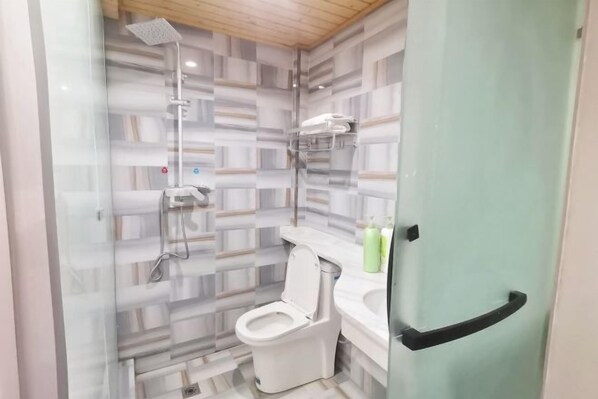 Un baño con ducha, inodoro y puerta de vidrio.