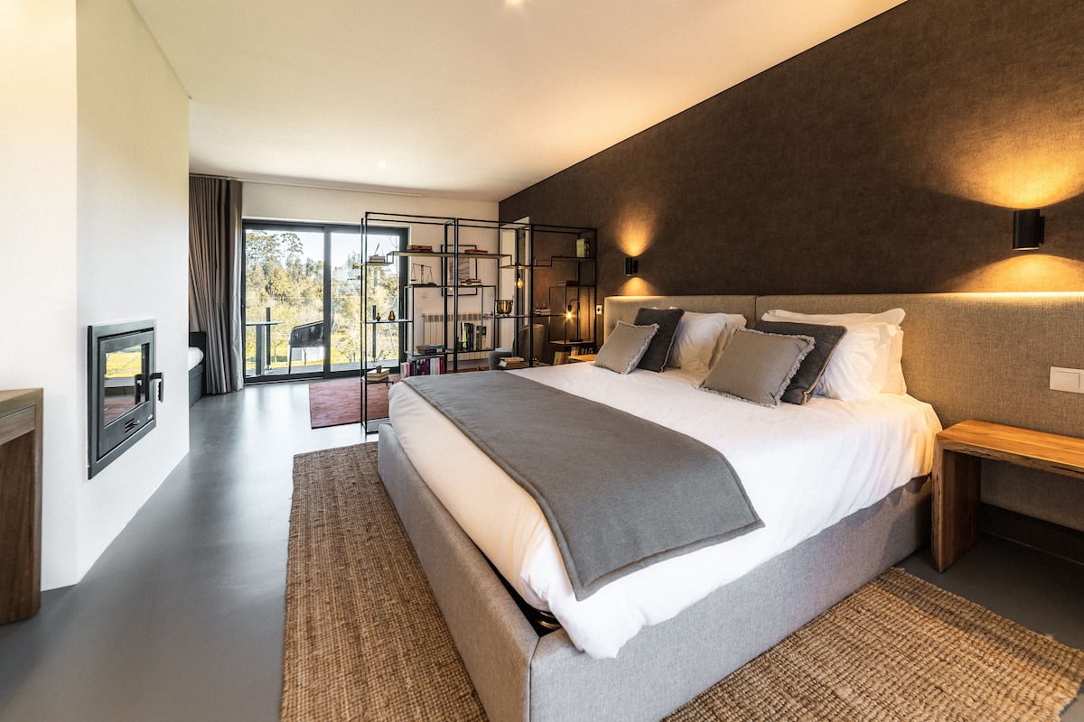 A modern bedroom with a large bed, a wooden bench, and a built-in bookshelf.