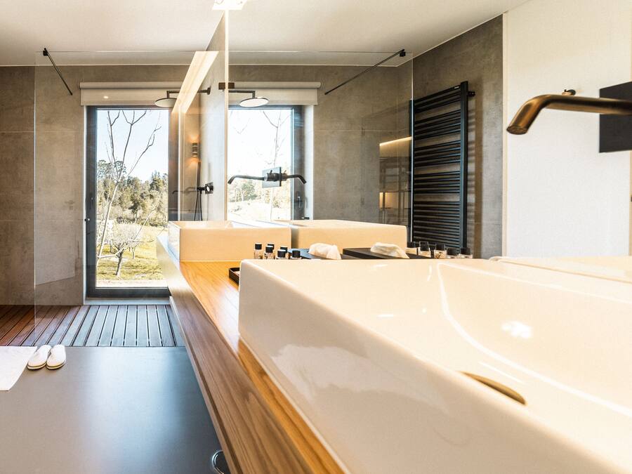 Un baño moderno con una bañera grande, piso de madera y vistas al exterior a través de una puerta de cristal.