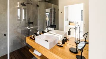 Un baño moderno con tocador de madera, dos lavamanos, un espejo grande y cabina de ducha con paredes de vidrio.