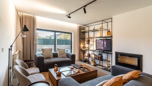 A modern living room with a sofa, armchairs, a coffee table, and a TV. - Granja da Cabrita (Coimbra)