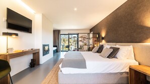 A modern bedroom with a large bed, bedside tables, a desk, and a TV mounted on the wall. - Granja da Cabrita (Coimbra)