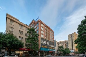 A multi-story building with commercial signage, a clear sky, and trees. - GeLi Hotel (Cenxi People's Hospital Bus Terminal) (Cenxi)