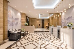 A hotel lobby with a reception desk, seating area, and a patterned floor. - GeLi Hotel (Cenxi People's Hospital Bus Terminal) (Cenxi)