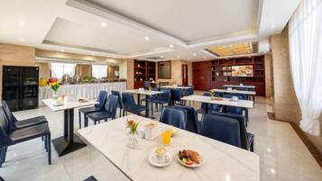 Un comedor de hotel con mesas, sillas y una barra de buffet.
