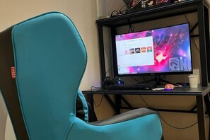 A teal gaming chair, a desktop computer with a colorful wallpaper, and a black desk. - GeLi Hotel (Cenxi People's Hospital Bus Terminal) (Cenxi)